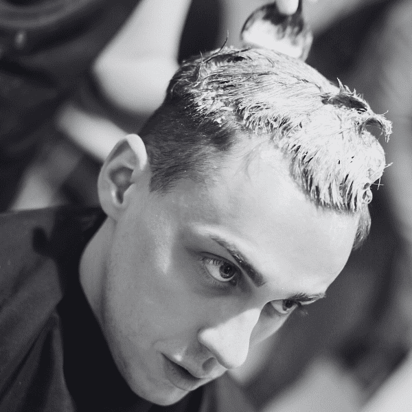Man getting hair dyed, seen in black and white, at a salon.